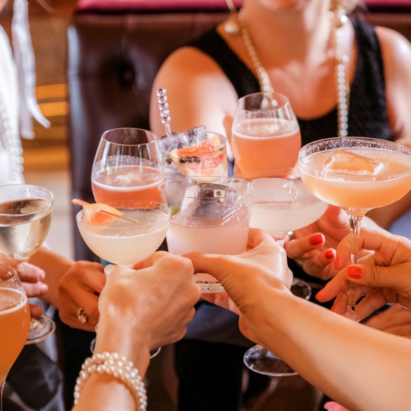 Close up of hands of a group of women enjoying cocktails at a private evening event